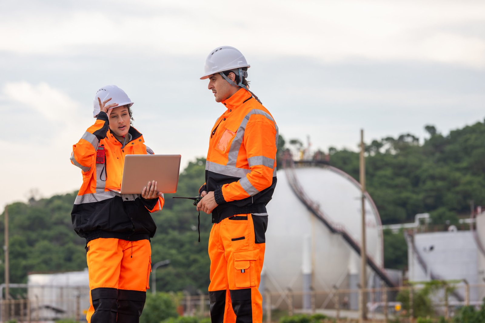 Engineers Collaborating at Industrial Site with Storage Tanks, Team of Engineers Conducting Operations at Oil Storage Field Industrial Site, Industrial Workers with Laptop Communicating at Site
